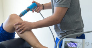 A patient receiving shockwave therapy on their knee.